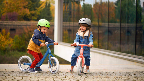 Two toddlers playing with their Kinderkraft Balance Bikes RAPID